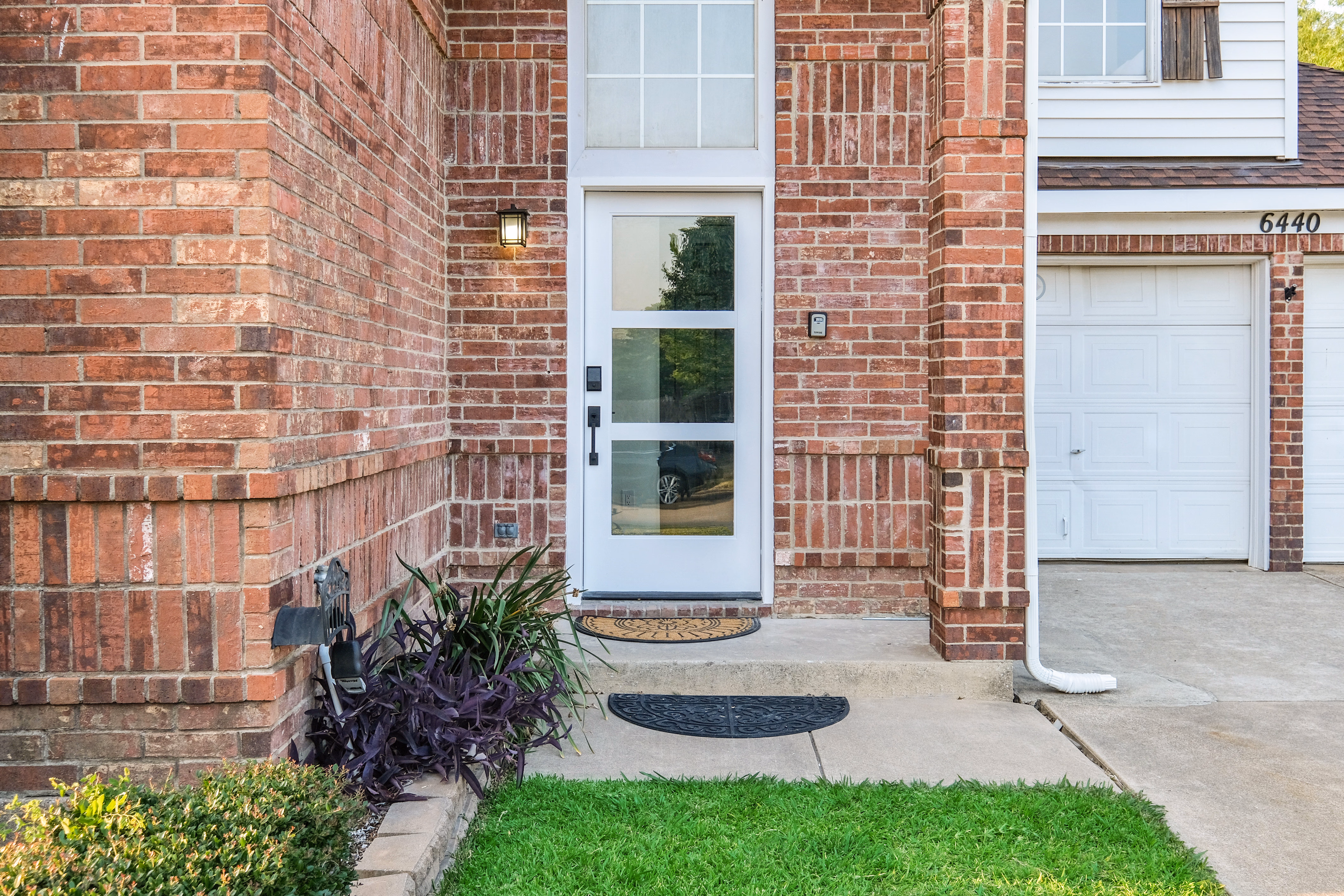 Front entry — white door, brick surround, sconce, house number 6440.