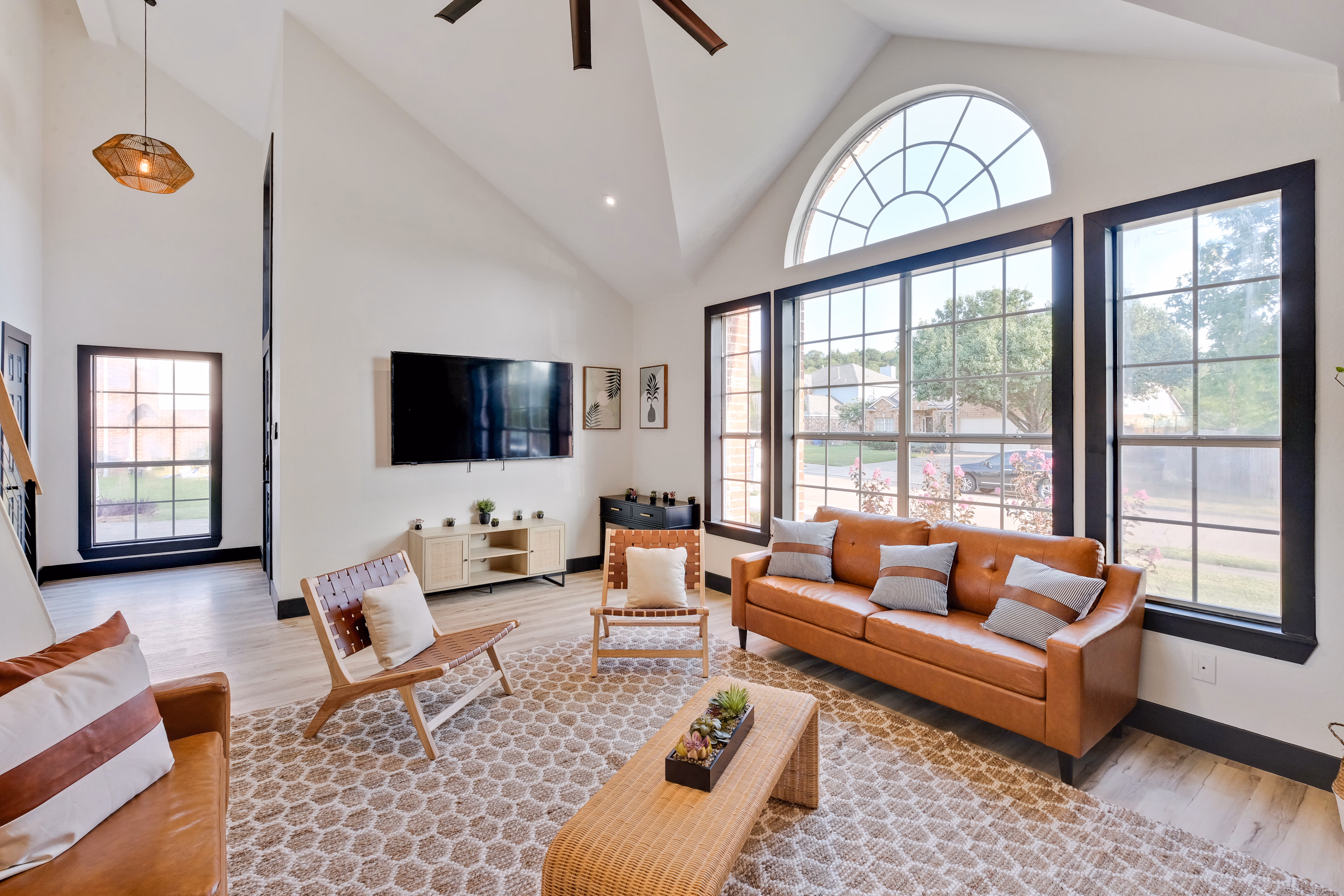 Living room — leather sofa, arched window, mounted TV.