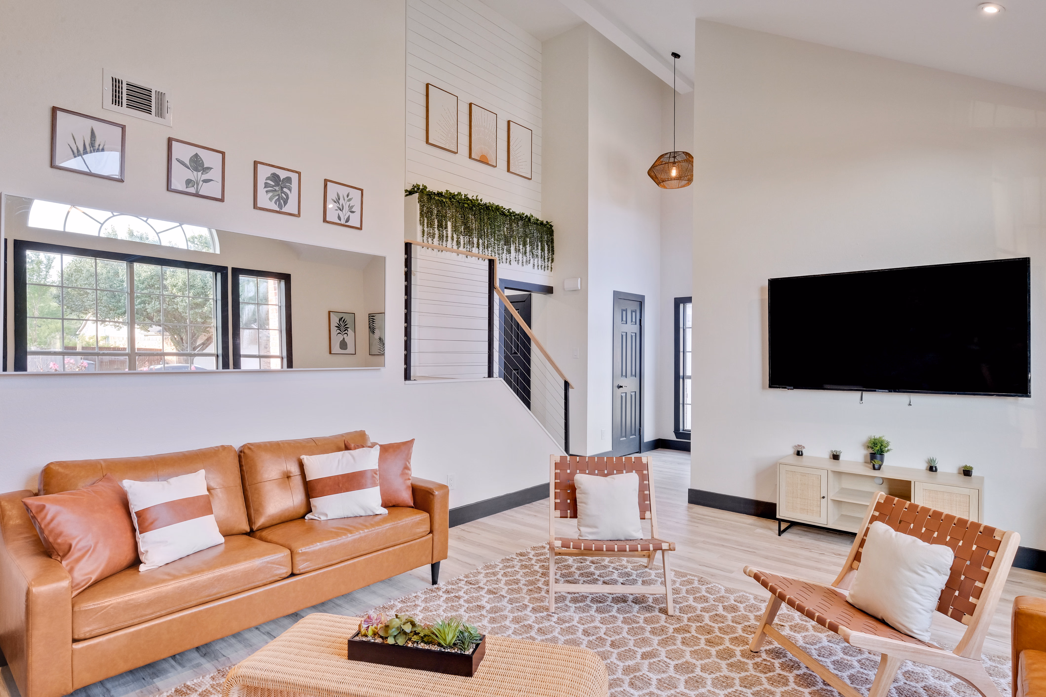 Living room — sofa, framed botanical prints, double-height ceiling.