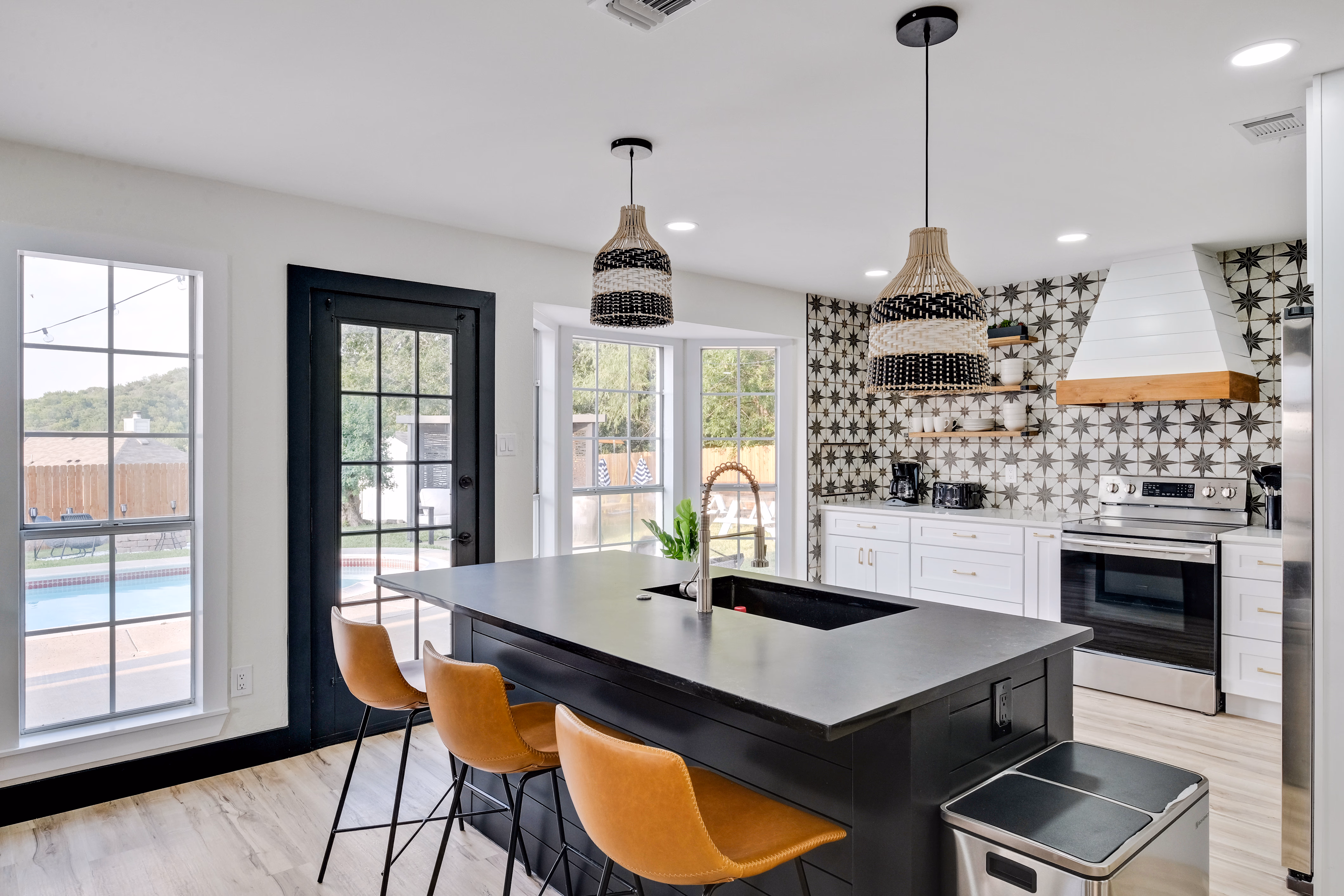 Kitchen island with three leather counter stools, pool view.