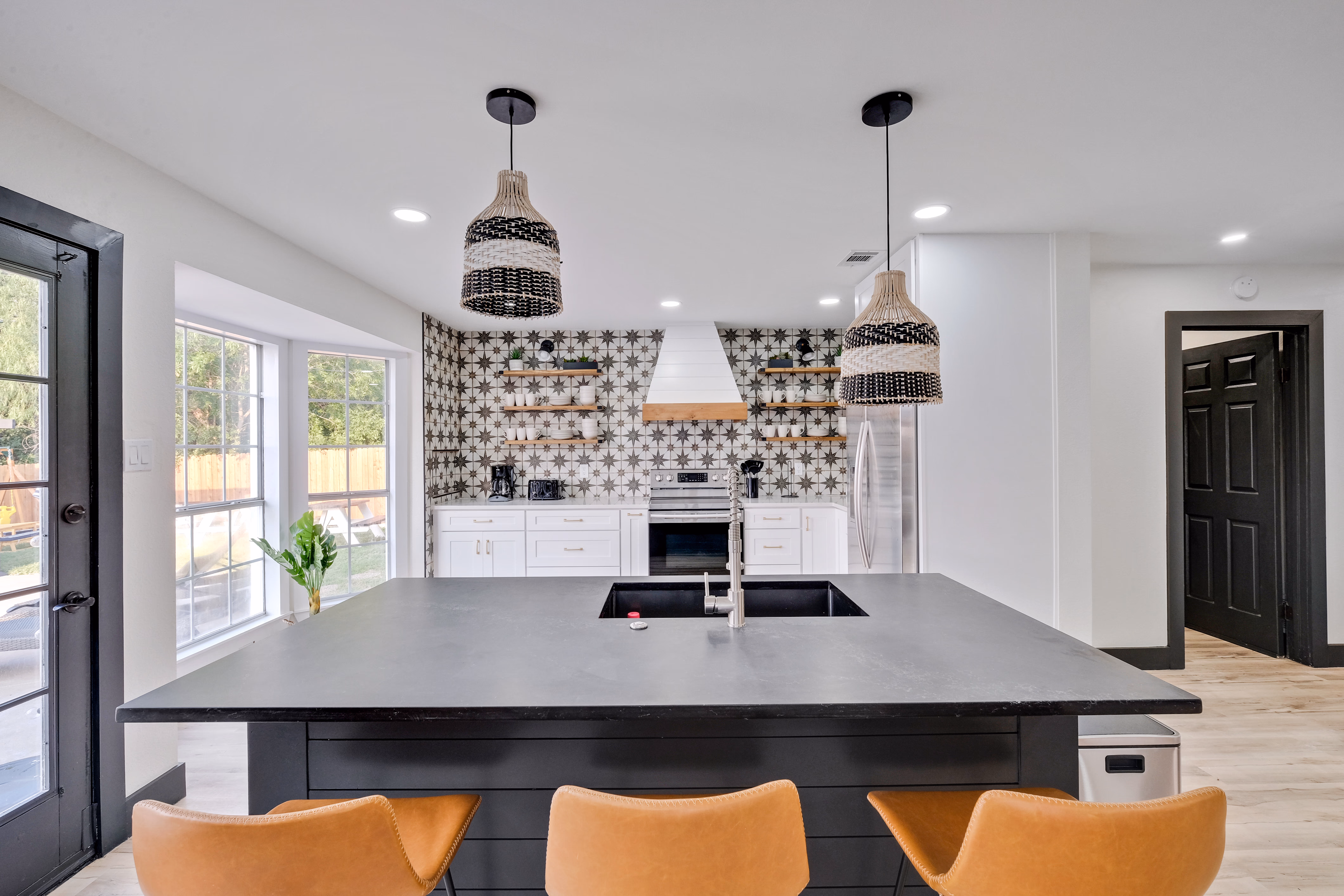 Kitchen island bar seating — pendant lights and patterned backsplash.