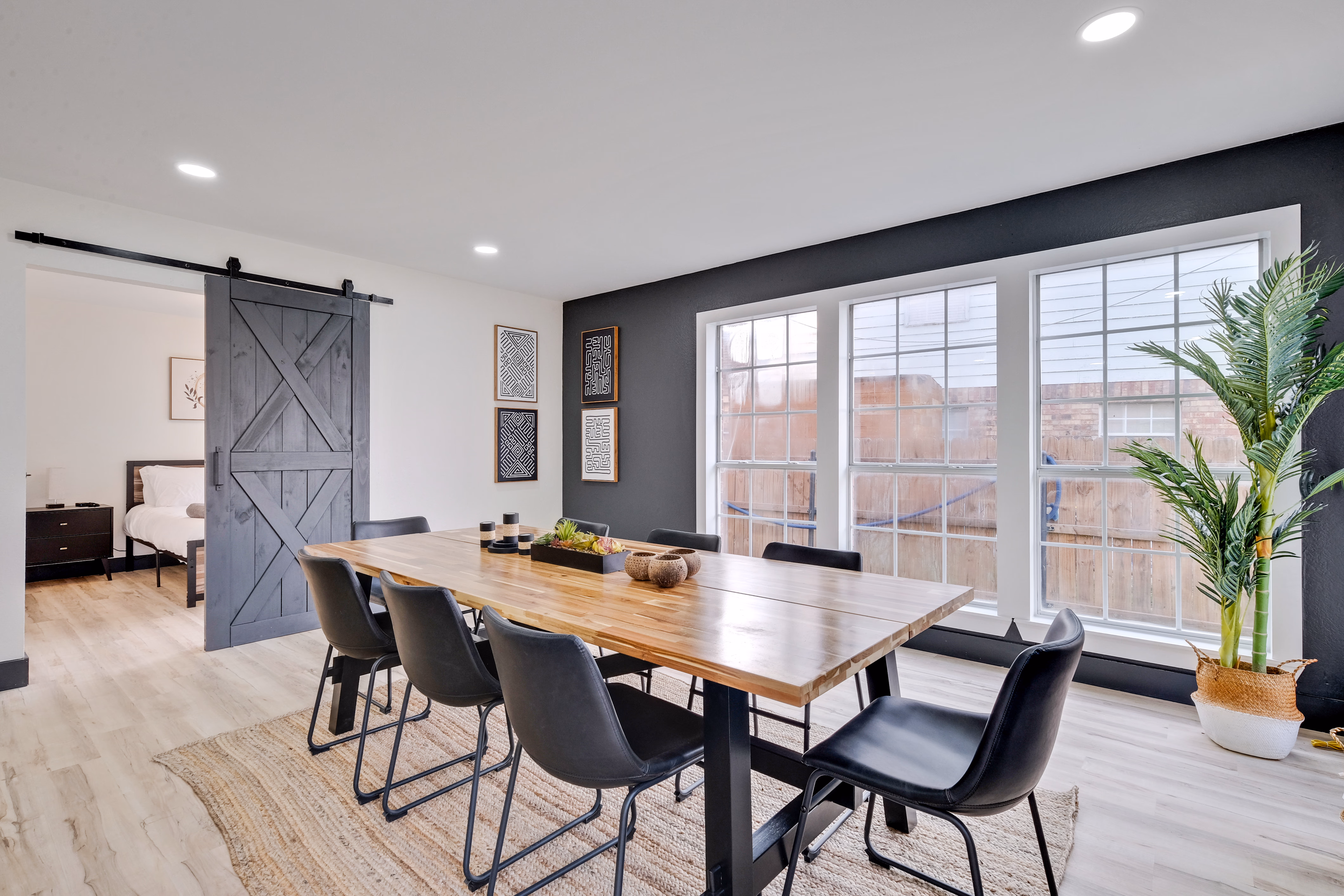 Dining room — long wood table, barn door opens to bedroom.