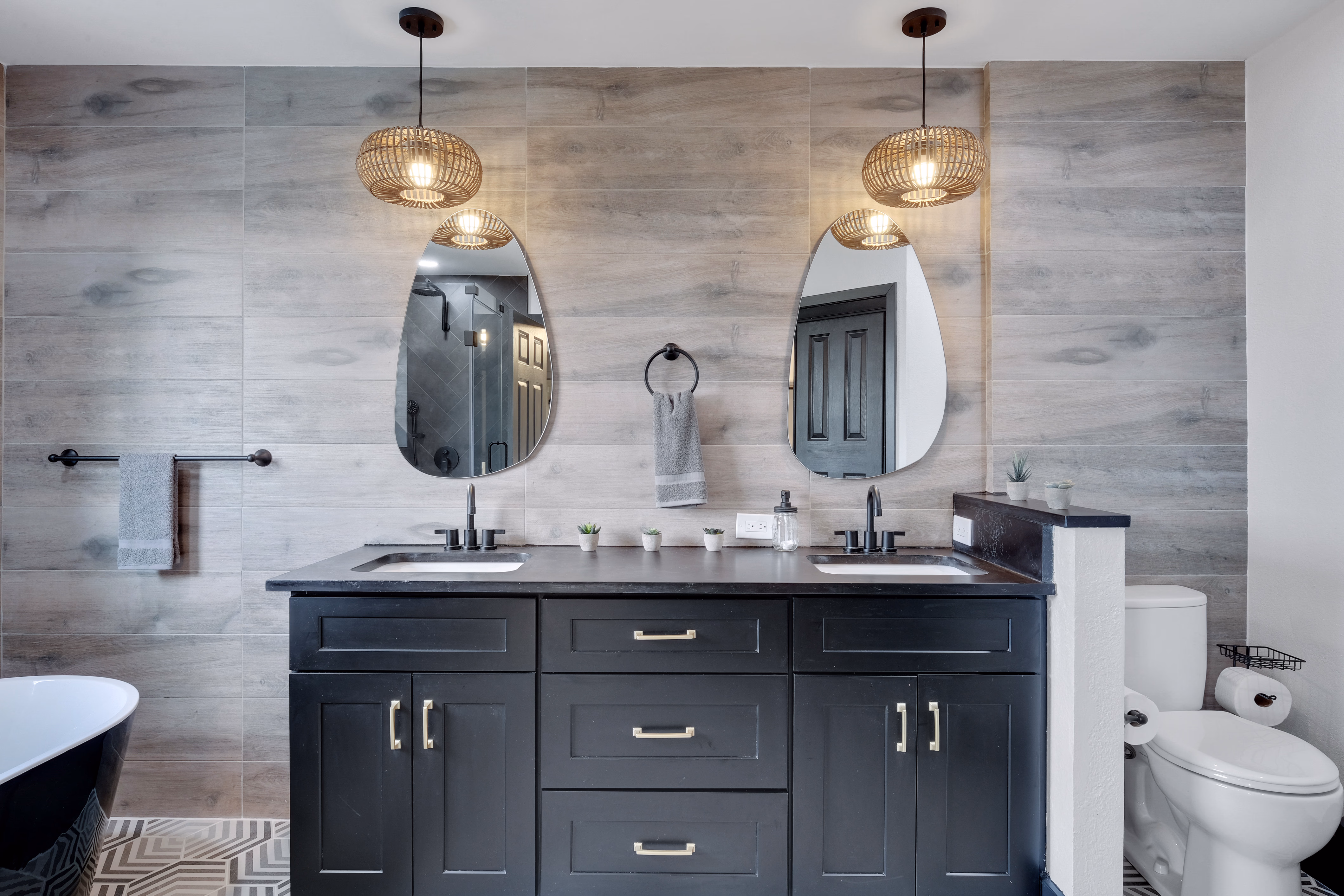 Master bath — dual vanity with rattan pendants and freestanding tub.