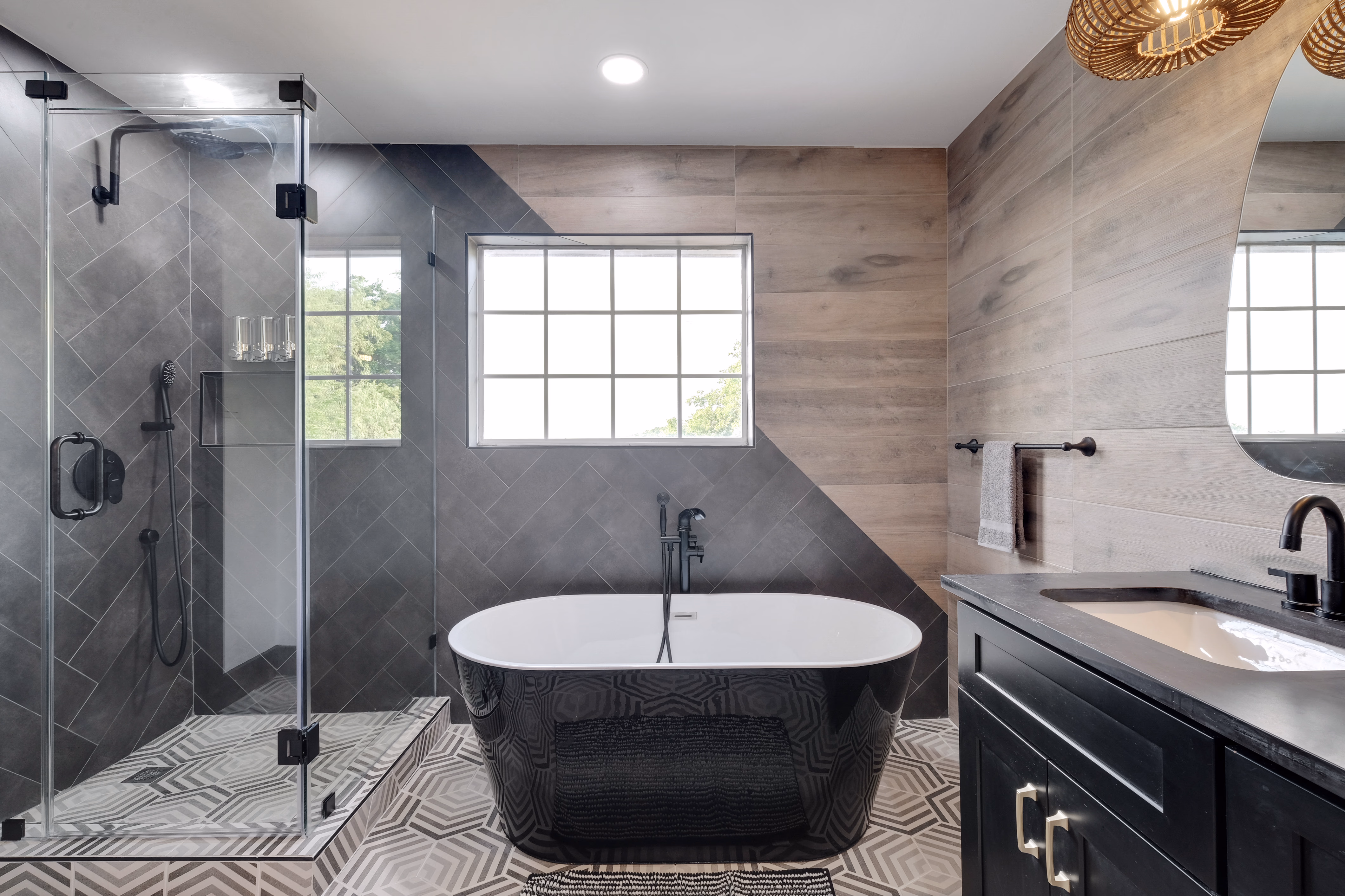 Master bath — glass shower, freestanding tub, geometric tile floor.