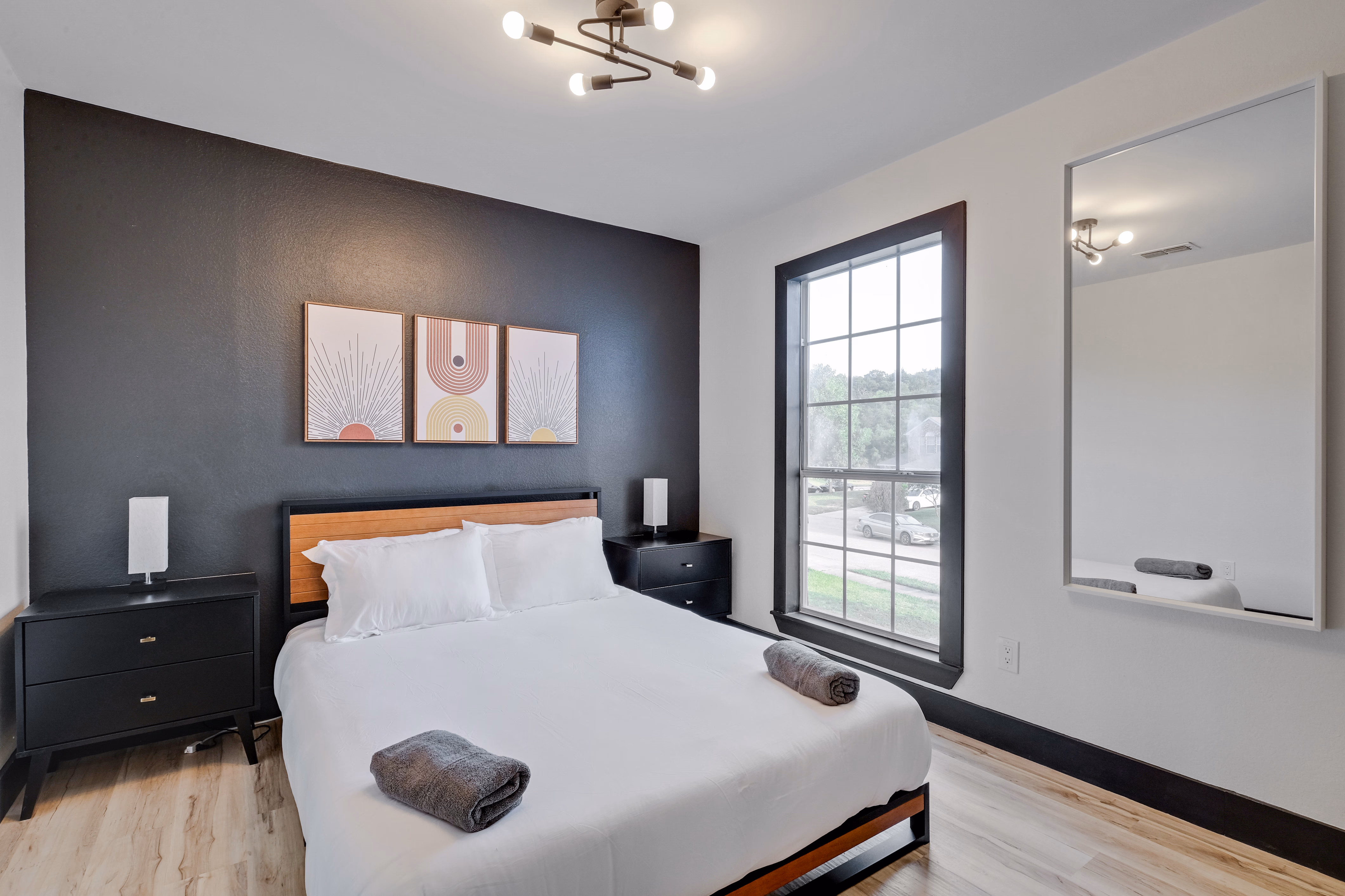 Bedroom — king bed, dark accent wall, large window with mirror.
