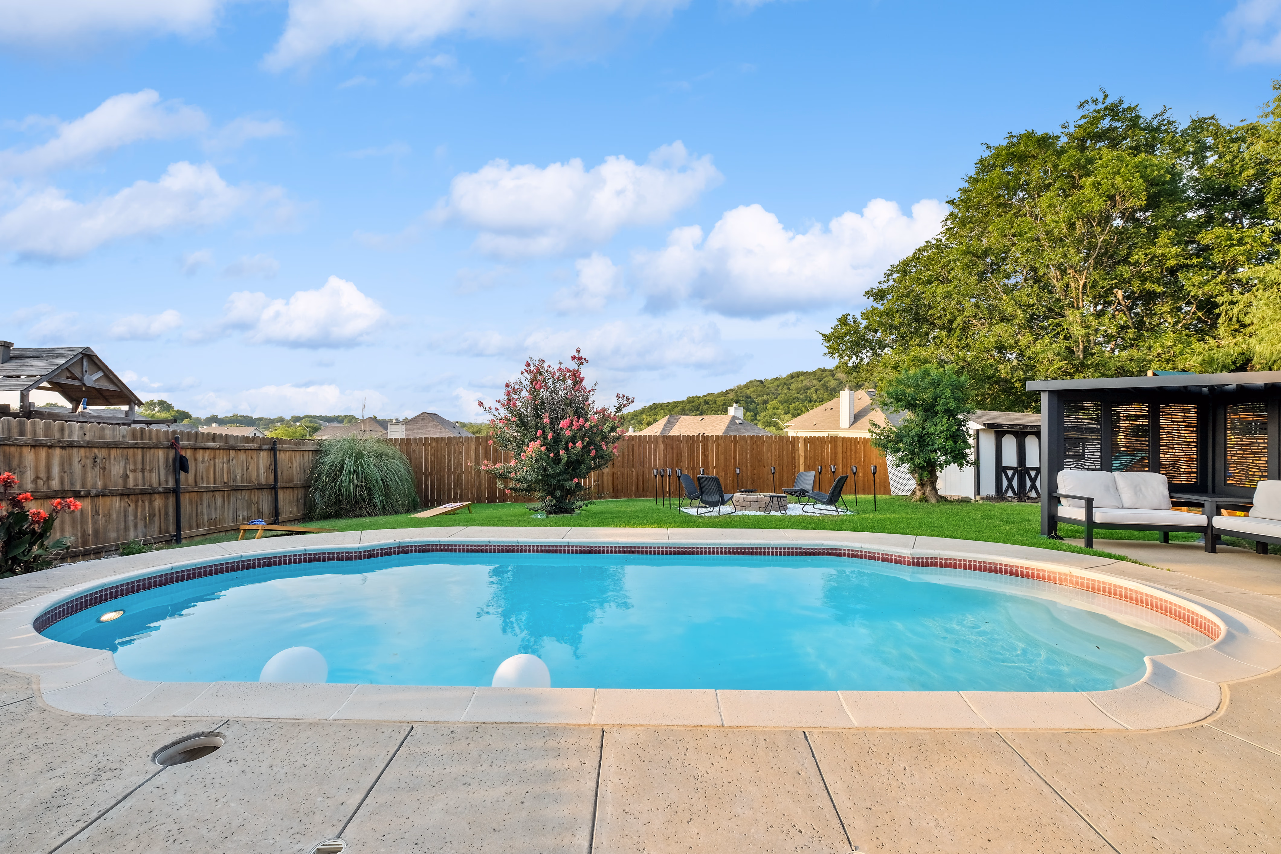 Pool with cabana sofa and yard view to hills.