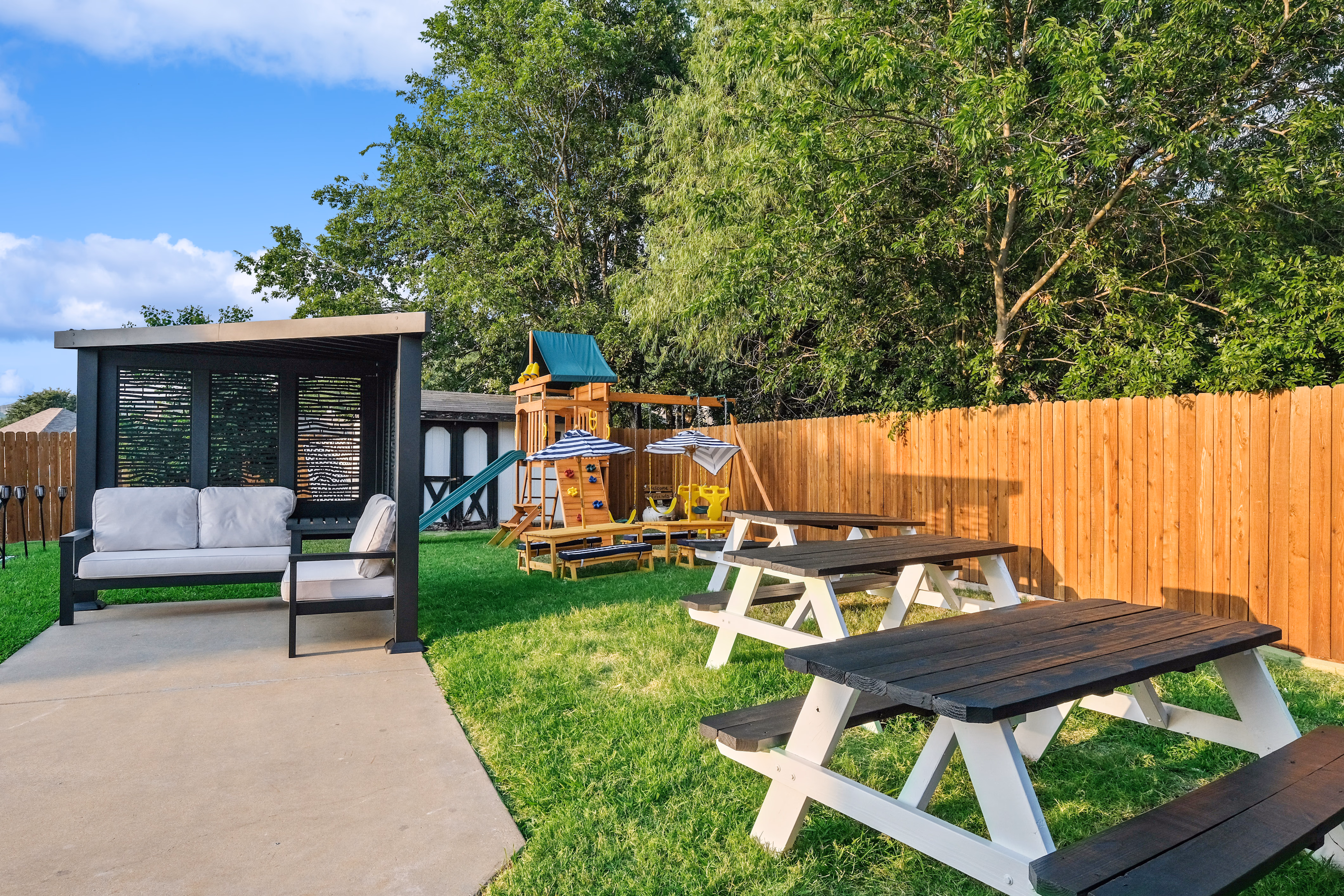 Backyard — cabana, picnic tables, playset and turf grass.