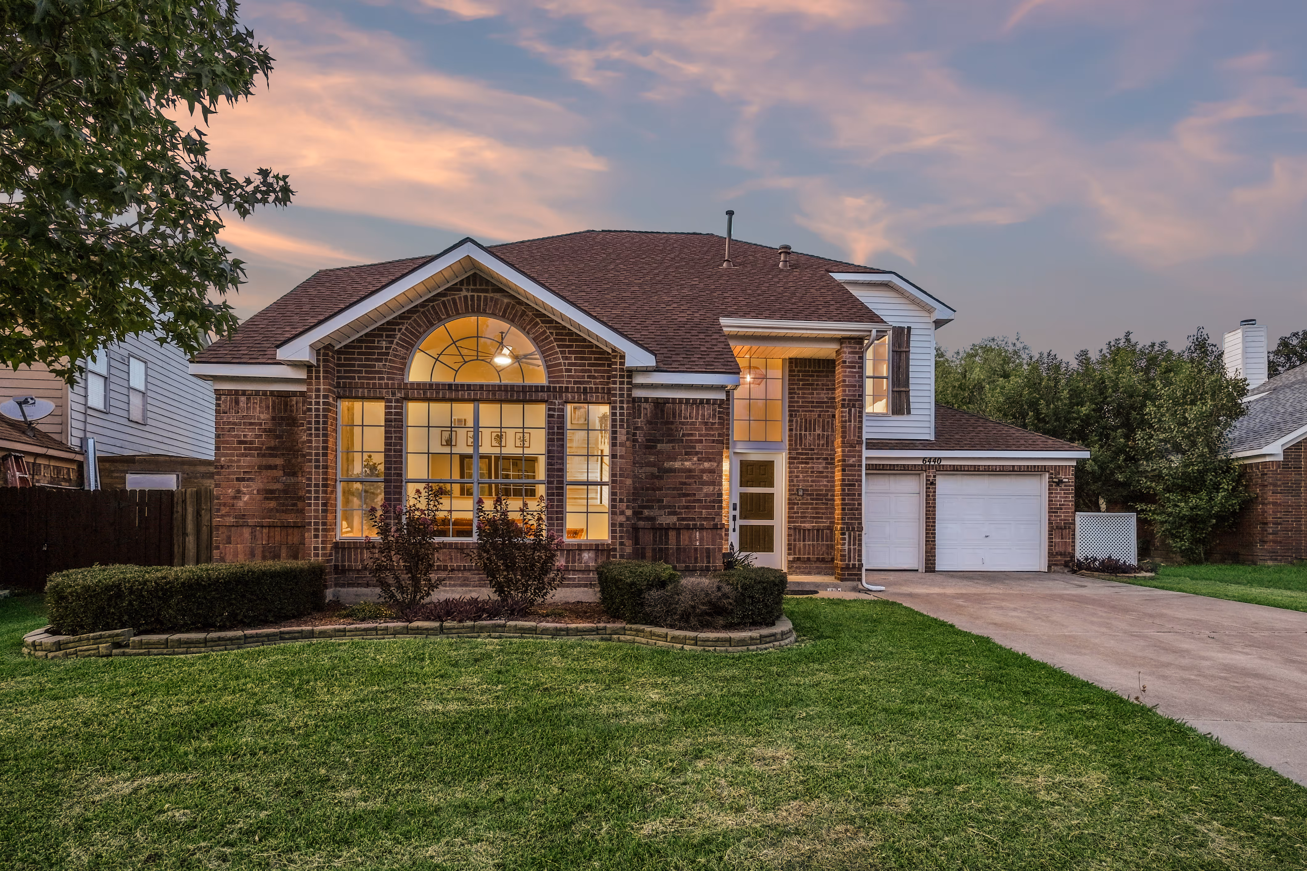 Knoll Ridge — Twilight front — arched window glowing, soft pink horizon.