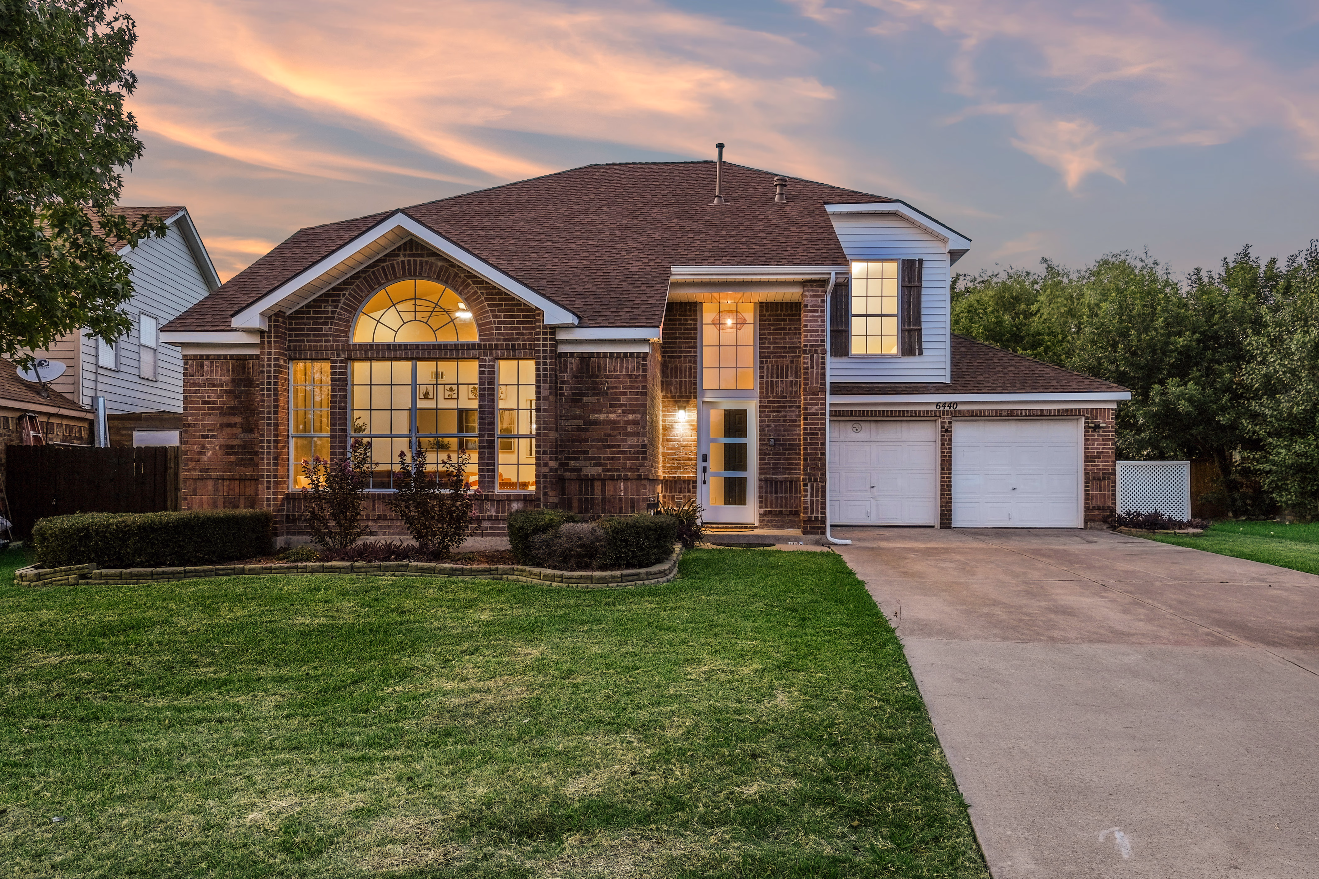Twilight facade with warm windows and tidy landscaping.